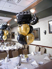 Black and gold Hollywood-themed balloon centerpiece with 6 latex balloons and movie camera mylar
