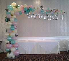 Colorful organic L-shape balloon arch with greens and custom name mylars