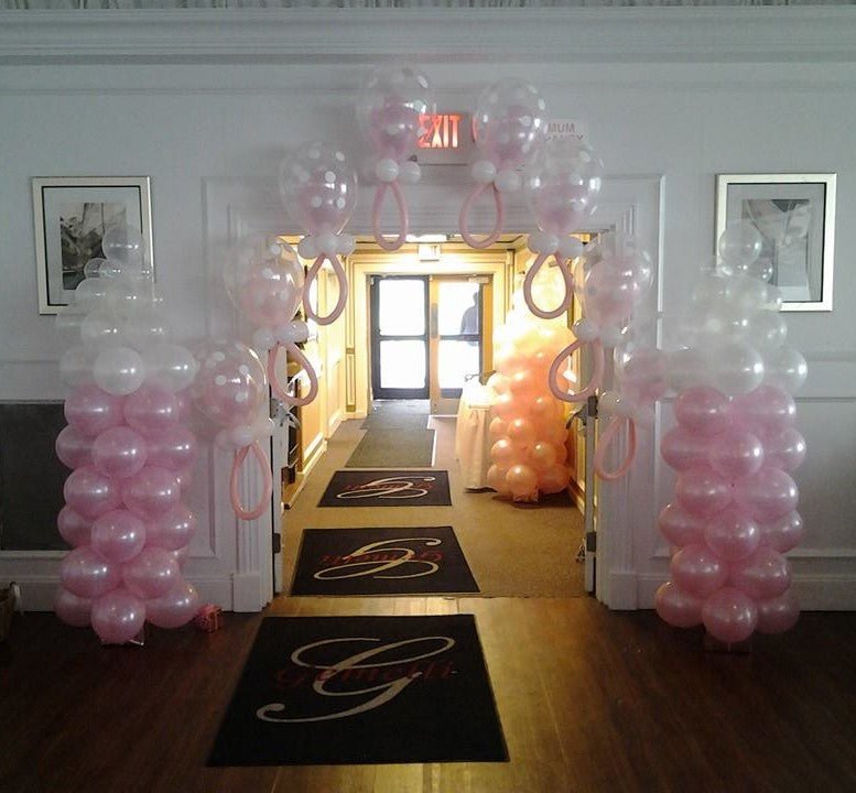 Pink and white pacifier balloon arch with matching balloon columns for baby shower décor