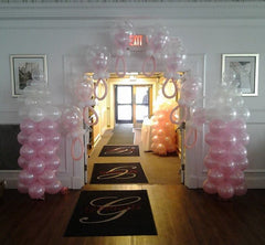 Pink and white pacifier balloon arch with matching balloon columns for baby shower décor