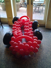 Race car balloon sculpture with red and black accents, party centerpiece