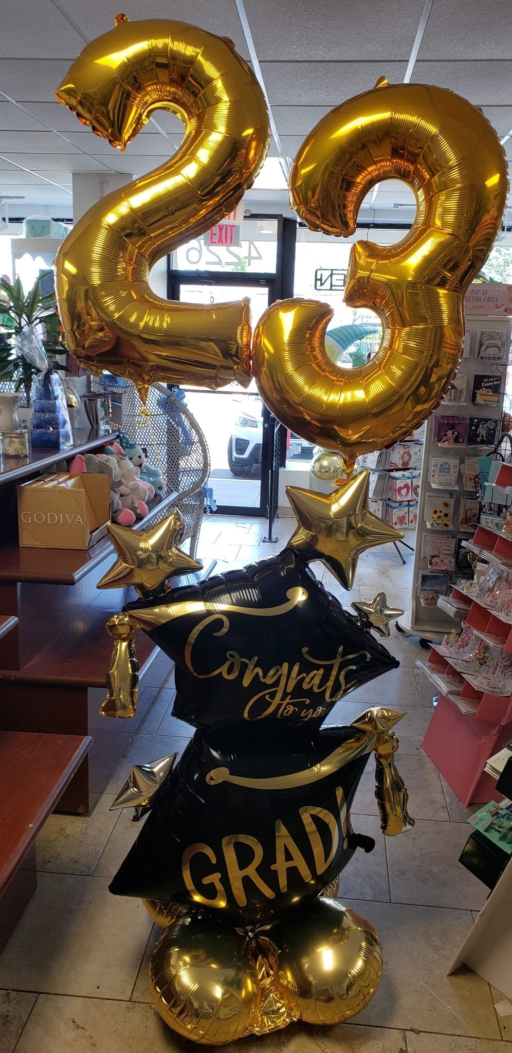 Congrats Grad balloon bouquet with gold number balloons and graduation-themed balloons on base