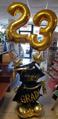 Congrats Grad balloon bouquet with gold number balloons and graduation-themed balloons on base