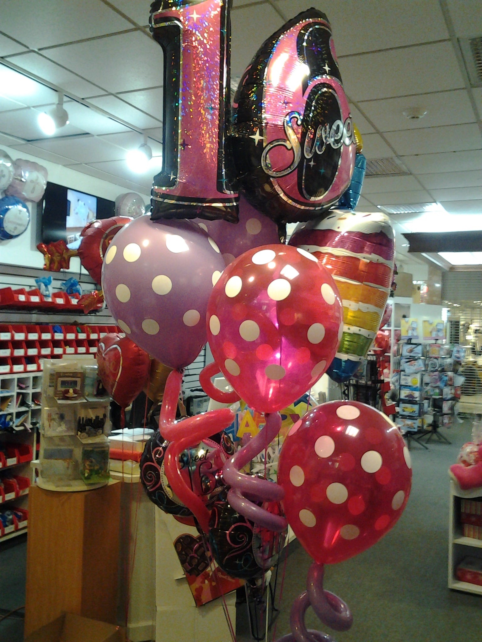 Sweet Sixteen balloon bouquet with jumbo Sweet 16 balloon, polka dot balloons, curly accents, rainbow cake balloon, and birthday mylars