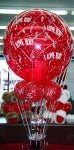 Romantic Valentine’s balloon arrangement with red and pink mylars and a display of Hershey’s Kisses candy