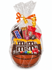 A clear cellophane gift bag tied with an orange and yellow ribbon, filled with assorted candy and a basketball-shaped M&M's milk chocolate bar, on a white background.